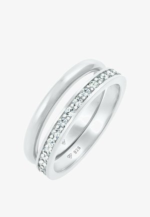 Twee zilveren ringen; een glad en afgerond, de ander met een rij kleine heldere steentjes die in een goot langs het midden zijn gezet. 925-markering zichtbaar.
