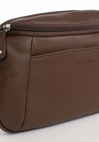 Pouch in pelle marrone con texture, dotato di una cerniera superiore e tasca frontale, con il discreto marchio embossato "Hexagona Paris".