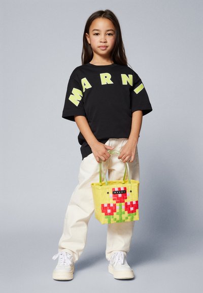 T-shirt oversized preta com letras em amarelo-neon "MARNI", calças cor creme e uma mala amarela trançada com um design floral.