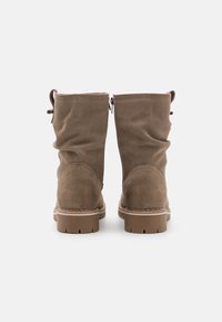 Bottines en suède marron avec un design froissé, bout rond et semelle en caoutchouc avec un motif texturé. Comprend des languettes pour un enfilage facile.