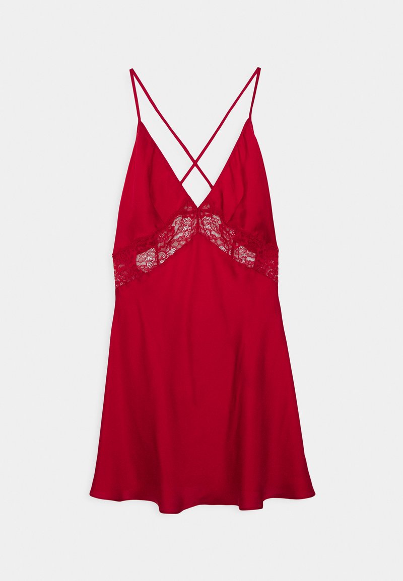 Κόκκινο σατέν φόρεμα slip με δαντελένια περιθώρια κάτω από το στήθος και λεπτές σταυρωτές τιράντες, κρεμασμένο μπροστά σε λευκό φόντο.