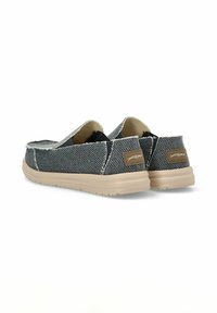 Zapatillas slip-on de lona en azul oscuro con un acabado texturizado, suela de goma beige y un sutil detalle de marca en el talón.
