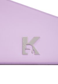 Lavendelfärgad läderväska med en silvrig logotyp "K" i profil. Designen är elegant med noggrant stygn längs kanterna.