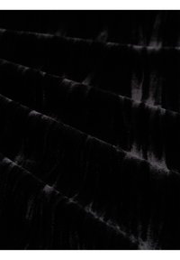 Tissu en velours noir avec des plis doux, montrant une texture lisse et réfléchissante en faible lumière.