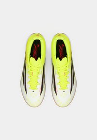 Ποδοσφαιρικά παπούτσια σε λάιμ κίτρινο χρώμα με λευκές και μαύρες λεπτομέρειες, υφή στην επάνω επιφάνεια και μαύρα κορδόνια, με σήμανση στη γλώσσα και στο πλάι.