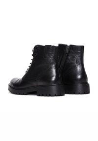 Botas de tobillo de cuero negro con un acabado texturizado, punta redonda, parte delantera con cordones y cremallera lateral. Cuenta con una suela robusta con diseño de agarre.