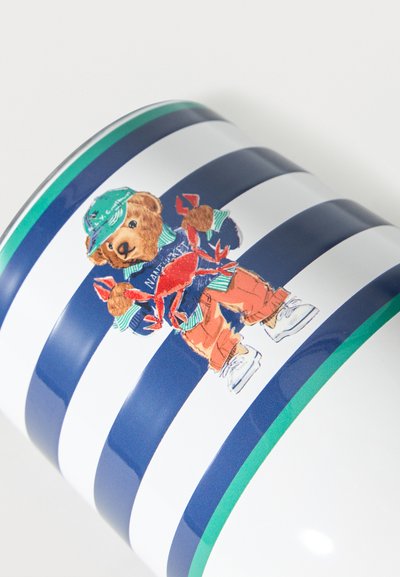 Kopp med marineblå og hvite striper, med et motiv av en bjørn som har på seg en grønn hatt, genser, oransje bukser, og holder en rød krabbe.