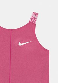 Różowy sportowy top na ramiączkach o gładkiej fakturze, z białym logo Nike z przodu i markowymi ramiączkami. Bezszwowy design z tyłu.