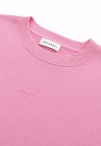 Sweat-shirt rose col rond avec col côtelé et broderie discrète "OH APRIL" ainsi qu'une étiquette à l'encolure.