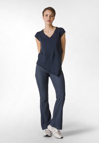 Námořnický tričko s krátkým rukávem a výstřihem do V, spárované s úzkými námořnickými kalhotami. Oblečení má měkkou, texturovanou látku a rozšířené konce kalhot.