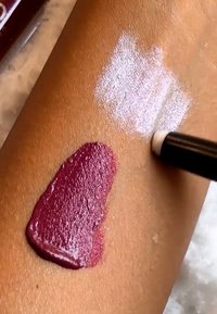 Dyp burgunderprøve og en hvit glimmerprøve på huden. Burgunder er blank, mens hvit har en matt tekstur med et svakt glimt.