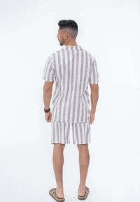 Chemise à manches courtes avec col et short assorti en tissu léger, présentant des rayures verticales marron et blanches, avec un design décontracté.