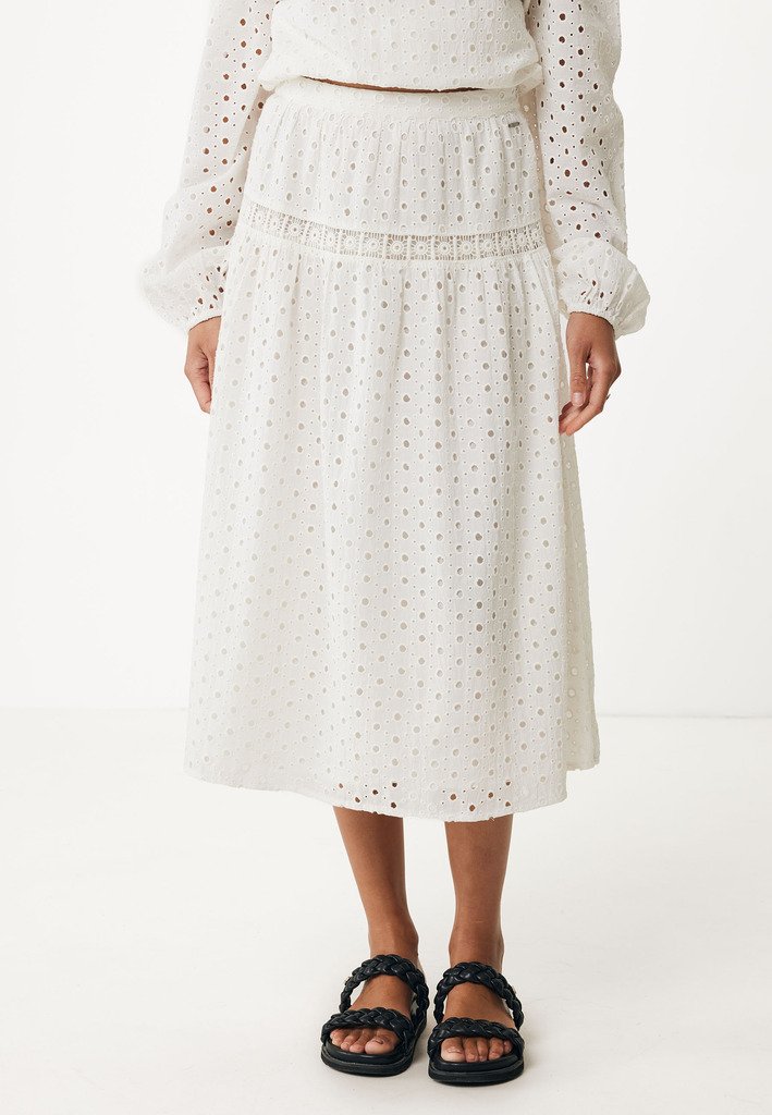 Vit midi kjol med ögonbladsdetaljer, elastisk midja och flerskiktad design. Bärs med svarta flätade sandaler.