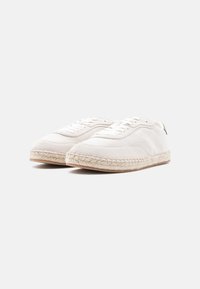 Λευκά πάνινα παπούτσια με στρογγυλή μύτη, σχεδιασμό με κορδόνια και πλεκτή λεπτομέρεια από τζούτ κατά μήκος της σόλας για επιπλέον υφή και λεπτομέρεια.