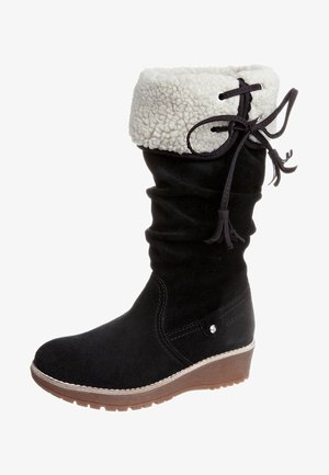 Czarny zamszowy but z białym mankietem z owczej skóry, marszczoną cholewką i klinową podeszwą. Posiada ozdobę zawiązywaną na sznurowadła oraz okrągły nosek.