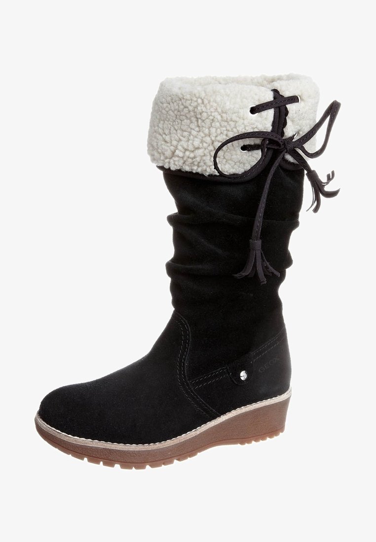 Botte en daim noir avec un bord en fourrure blanche, tige froncée et semelle compensée. Elle présente un détail lacé et un embout arrondi.