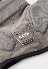 Suport pentru încheietura mâinii de culoare gri, cu o suprafață texturată, accente din cauciuc și o etichetă cu logo-ul CDS. Prezentă perforații pentru respirabilitate. Finisaj din material moale.