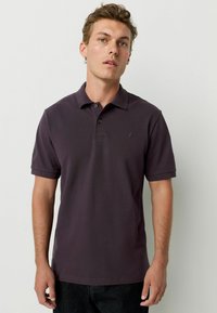 Tummanvioletti polo-paita, joka on valmistettu puuvillasta, ominaisuuksinaan klassinen kaulus, lyhyet hiharesorit ja pieni kirjailtu logo rinnassa.