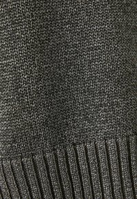 Pull en maille gris foncé avec un motif texturé, doté de détails côtelés à l'ourlet. Le matériau semble doux et flexible.