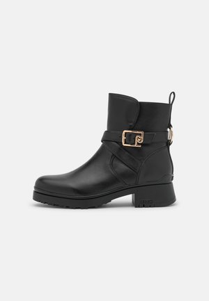 Schwarzer Knöchelstiefel mit niedrigem Blockabsatz, Goldschnallenriemen-Detail und Zuglasche hinten, ausgestattet mit einer robusten Sohle für besseren Halt.