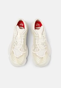 Scarpe da ginnastica bianche con motivi ondulati e testurizzati in beige chiaro. Design con lacci e interno rosso, con un marchio sottile sui lati.