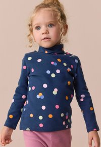 Marineblå langærmet turtleneck med farverige prikker i forskellige størrelser. Blødt stof med tæt pasform. Sammen med pink ribbede bukser.