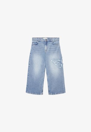Shorts di jeans a gamba larga azzurri chiaro con una toppa a farfalla sfrangiata sulla coscia destra anteriore e dettagli tradizionali di tasca e bottone.