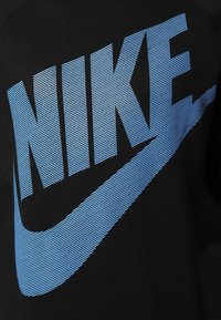 Černá mikina s výrazným modrým logem Nike, s horizontálními pásy tvořícími písmena a swoosh, což vytváří texturovaný efekt.
