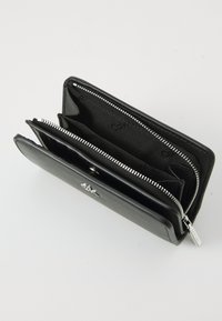 Black leather wallet with a textured finish, featuring silver hardware, multiple compartments, and a zip closure, displaying interior branding.