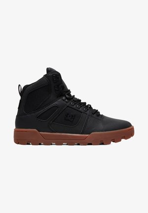 Black high-top shoes made of leather and mesh, featuring a brown rubber sole, reinforced toe, and mesh side panels for breathability.