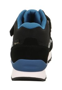 Černé a modré tenisky viděné z vzadu, s polstrovaným límcem, označením Gore-Tex a silnou bílou podrážkou s černým vzorkem.