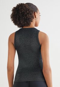 Zwarte mouwloze top gemaakt van reflecterend materiaal, met een aansluitend ontwerp en geribbelde textuur bij de halslijn en onderrand.