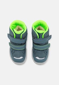 Zapatos para niños con capucha azul y forro de malla verde, dos correas de Velcro, suelas de goma grises y acentos blancos en la punta y los laterales.