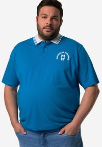 Modrá polo košile s bílým pruhovaným límcem, předními knoflíky a potiskem loga. Vyrobena z bavlny, má krátké rukávy a volný střih.