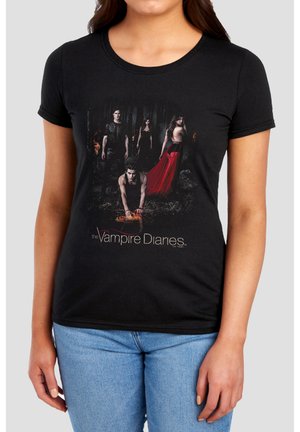 Four characters in dark clothing stand and crouch in a forest with flames; one woman wears a flowing red skirt, "The Vampire Diaries" text below.