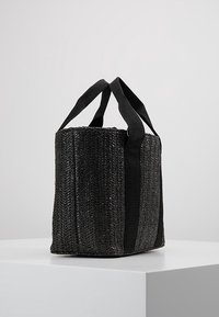 Bolso negro tejido con un patrón texturizado, de forma rectangular y con dos asas de tela. Material duradero para el uso diario.