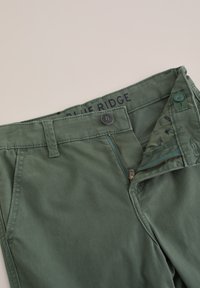 Groene katoenen broek met een rits- en knoopsluiting. Voorzien van een label met de tekst "BLUE RIDGE" en een gewatteerde binnenvoering.