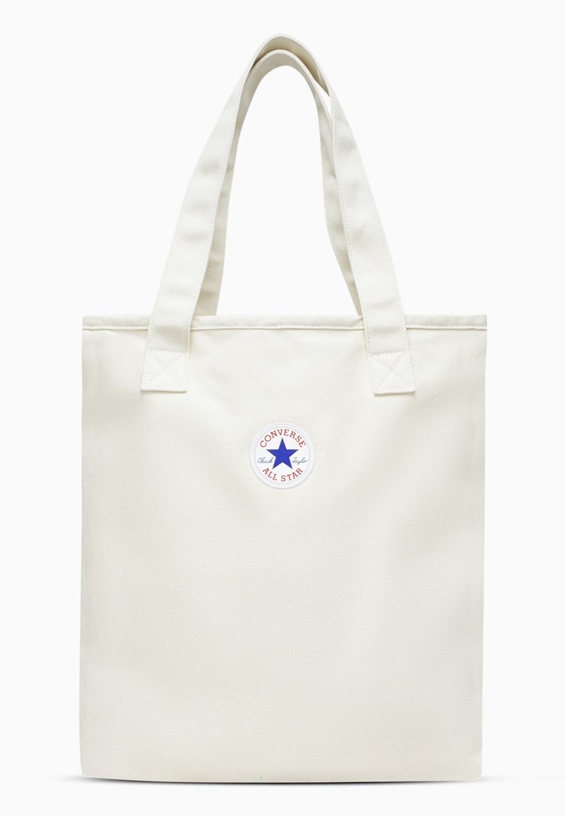 Kreminės spalvos drobės rankinė su dviem rankenomis. Viduryje yra apvalus raudonas ir mėlynas Converse All Star logotipas.