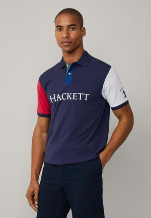 Marineblauw polo-shirt met rode, witte en groene accenten. Voorzien van geborduurd "HACKETT" logo. Klassieke kraag en korte mouwen. Katoenen gemengde stof.