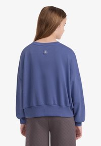 Μπλε φούτερ με άνετη εφαρμογή, στρογγυλή λαιμόκοψη και ριμπ μανσέτες. Διαθέτει μικρό λογότυπο στο πάνω μέρος της πλάτης. Μαλακή υφή υφάσματος.