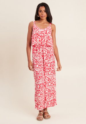 Rote und weiße gemusterte Jumpsuit mit einem Rüschenshirt, weitem Bein und Bindegürtel. Das Material scheint leicht und fließend zu sein.