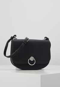 Borsa a tracolla in pelle nera con forma curva, hardware argentato, un accento circolare e una tracolla regolabile. Texture liscia, design minimalista.