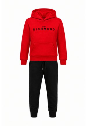 Felpa con cappuccio rossa con testo nero "John Richmond", abbinata a pantaloni jogger neri con coulisse.