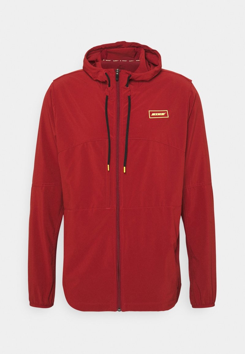 Veste à capuche rouge Nike avec fermeture éclair à l'avant, cordons noirs à embouts jaunes et petit logo rectangulaire sur la poitrine.