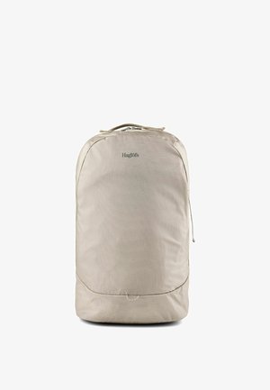Sac à dos rectangulaire beige avec bords arrondis, poignée supérieure, fermeture éclair et nom de marque "Haglöfs" au centre avant.
