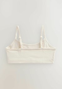 Bralette color crema con spalline sottili e regolabili, in morbido cotone e con un design semplice e senza cuciture. Scollo arrotondato e fascia sotto il busto.