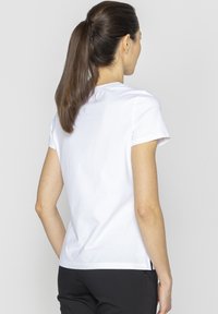 Biała bawełniana koszulka z krótkim rękawem, okrągłym dekoltem i prostym krojem. Brak widocznych wzorów lub dodatków.