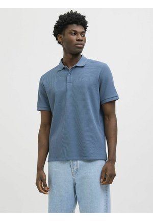 Blaues strukturiertes Poloshirt mit Kragen, kurzen Ärmeln und einem dezenten Logo. Trägt man zu hellblauen Jeans.