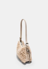 Borsa beige con materiale fluffy texturizzato su un lato, pelle liscia dall'altro, una tracolla sottile e dettagli in metallo.