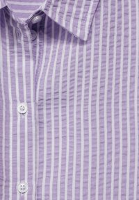 Lila randig skjorta med krinklad textur, som har tunna vita vertikala ränder, en spetsig krage och vita plastknappar.